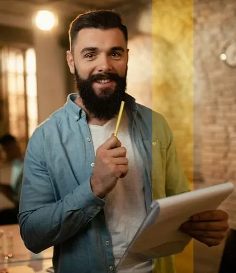 homem sorrindo com caneta e caderneta, sorriso para demonstrar a satisfação de trabalhar na agencia isaques estudios